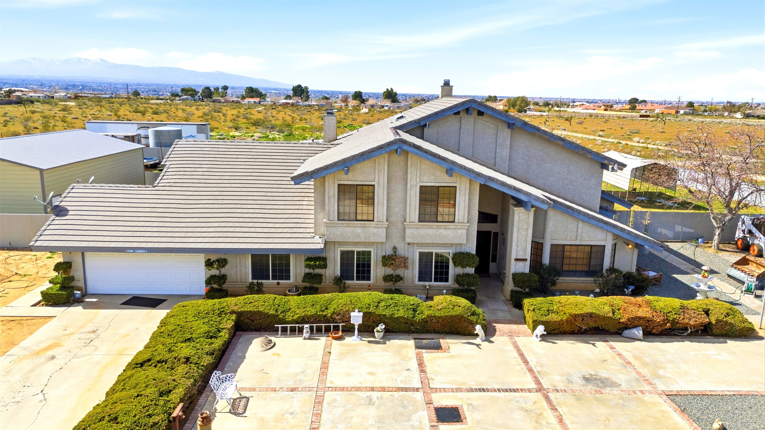 Front aerial view of 11468 Kiowa Rd Apple Valley with driveway and workshop in view